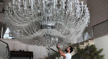 Luciano Camargo ficou pequeno perto do lustre gigantesco que ilumina a sala principal de sua mansão - Foto: Reprodução/ Instagram